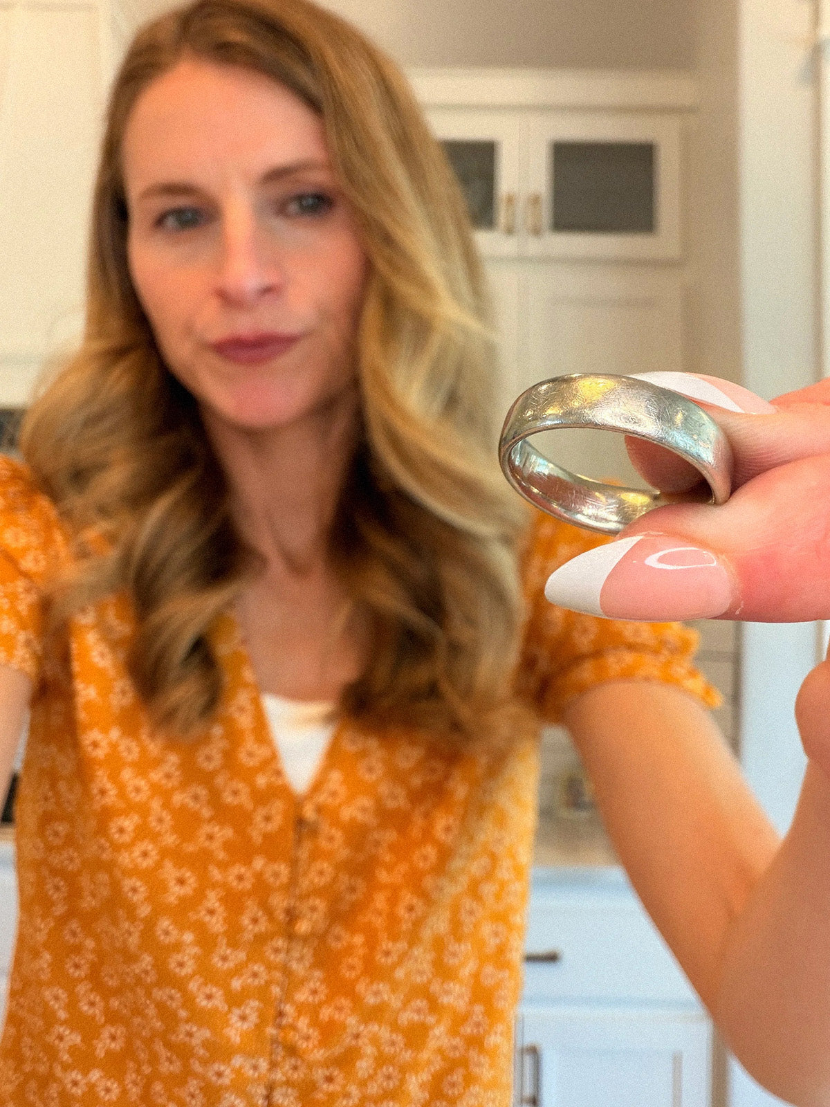 Woman holding a dull silver ring showing daily wear tarnish, before polishing with Buhron silver polishing cloth